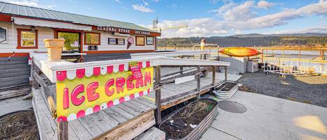 An ice cream shop with a wooden deck and a view of a lake and mountains in the background.