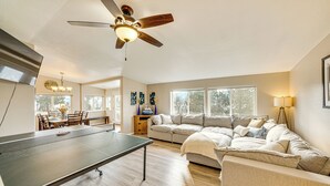 A spacious living room with a ping pong table, a sofa, and a ceiling fan. - Walk to Marina: Harrison Cabin w/ Lake View! (Harrison)