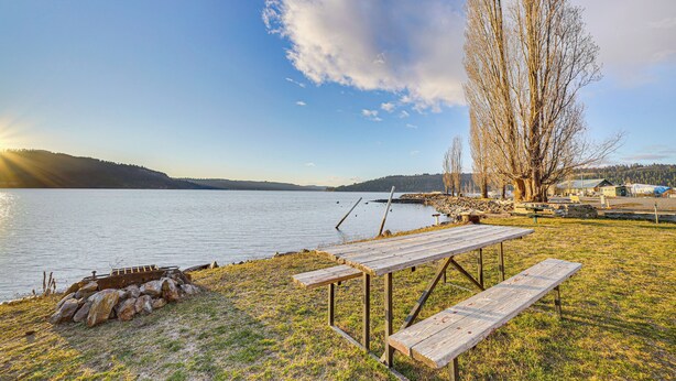 A lakeside picnic area with a wooden bench and picnic table, surrounded by trees and a view of the lake. - Walk to Marina: Harrison Cabin w/ Lake View! (Harrison)