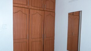 Ein Zimmer mit großem Holzschrank, kleinem Fenster und Fliesenboden.