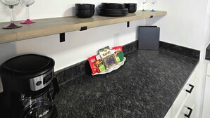 Een keuken met zwart zeshoekig wanddecor, een koffiezetapparaat en diverse keukenspullen op planken.