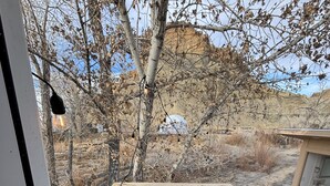 A wooden deck with a welcome mat and a sign, overlooking a dry landscape with sparse trees. - Capitol Reef Dome | Willow (Hanksville)