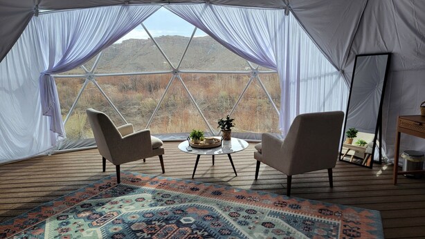 A tented room with two chairs, a small table, and a rug. - Capitol Reef Dome | Willow (Hanksville)