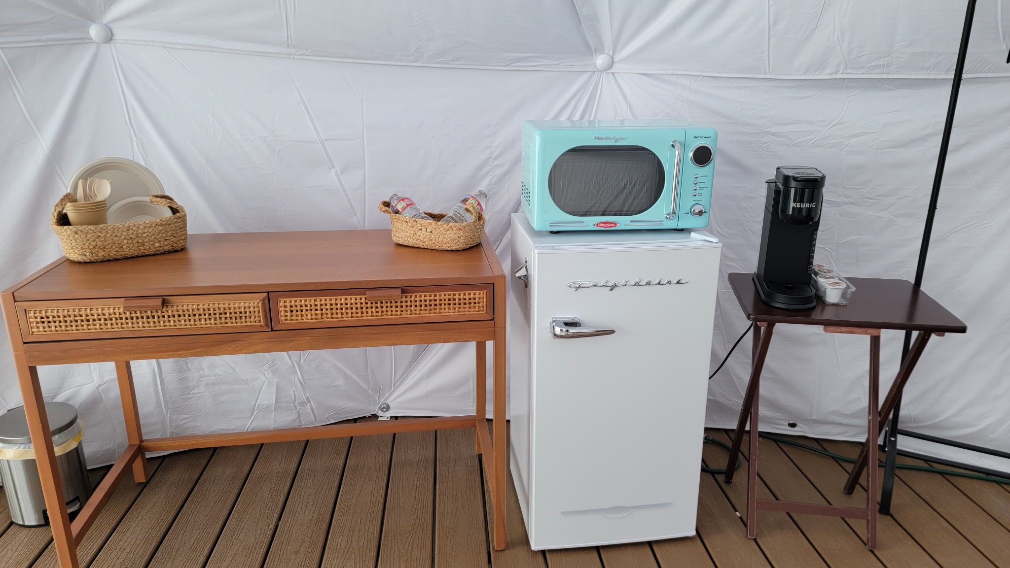 Una kitchenette compacta con un refrigerador blanco, un microondas de estilo retro y una cafetera sobre una mesita.
