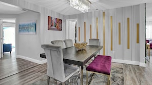A dining area with a wooden table, grey upholstered chairs, and a chandelier. - Heated Pool, Spa (Clearwater)
