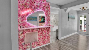 A salon with a pink floral backdrop and a neon sign. - Heated Pool, Spa (Clearwater)