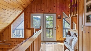 A wooden interior with a balcony, a bench, and a door leading outside. - Bear Hideaway (Sevierville)