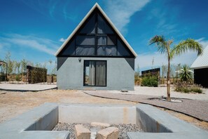 A modern house with a triangular roof, a large window, and a concrete structure in the foreground. - La Campiña Glamping Club (El Llano)
