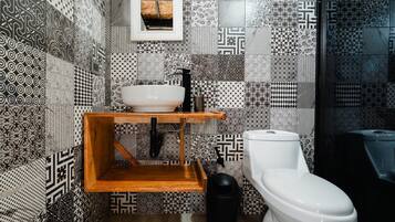 A bathroom with a white toilet, a wooden shelf with a sink, and patterned tiles on the walls.