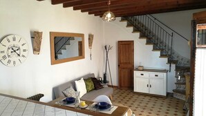 A living room with a wooden ceiling, a dining area with a table set for two, a staircase, and a white cabinet. - Single Family Home in Andratx (Andratx)