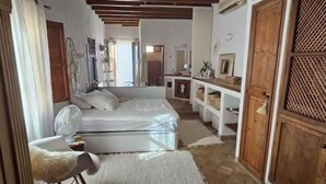 A room with a bed, a fan, a wooden door, and a white wall. - Single Family Home in Andratx (Andratx)