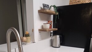 Een moderne keuken met een wit aanrecht, een roestvrijstalen spoelbak en een ingebouwde koffiezetapparaat.