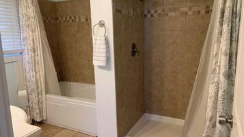 A bathroom with a shower, toilet, and bathtub.