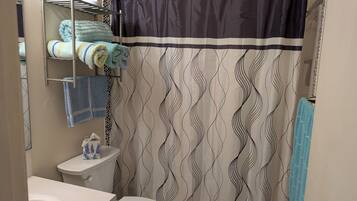 Une salle de bain équipée de toilettes, d’un lavabo, d’un porte-serviettes et d’un rideau de douche.