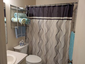 A bathroom with a toilet, sink, towel rack, and shower curtain. -  3-bedroom Home away from home while in Rockdale A (Rockdale)