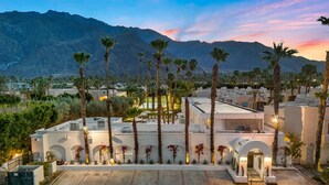 Un hotel con un cortile interno, palme e montagne sullo sfondo.