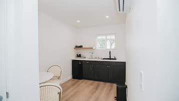 Een compacte keuken met een eethoek, met een klein keukeneiland, donkere kasten en een raam met uitzicht.