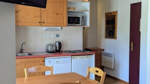 A compact kitchen with wooden cabinets, a microwave, a toaster, and a sink.