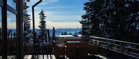 A wooden deck with a view of snow-covered trees and mountains.