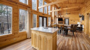 A spacious wooden cabin with large windows, a kitchen area, and a dining space.