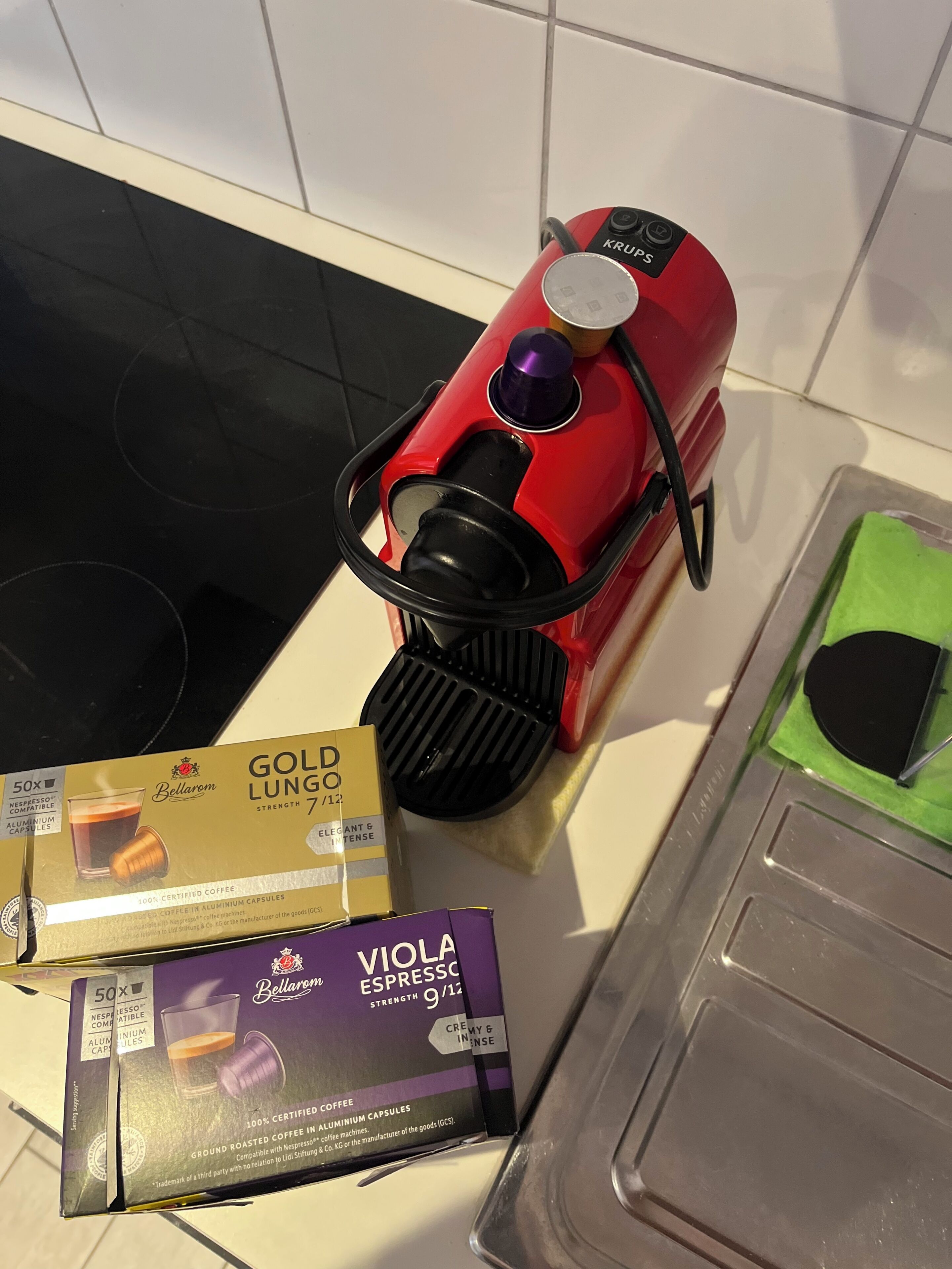 Een koffiezetapparaat, een doos Gold Lung koffiecapsules en een doos Viola Espresso capsules op een keukentafel.