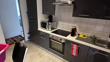 Una cucina moderna dotata di forno a microonde, forno e lavello. Si nota una sedia e un tavolo con una tovaglia decorata.
