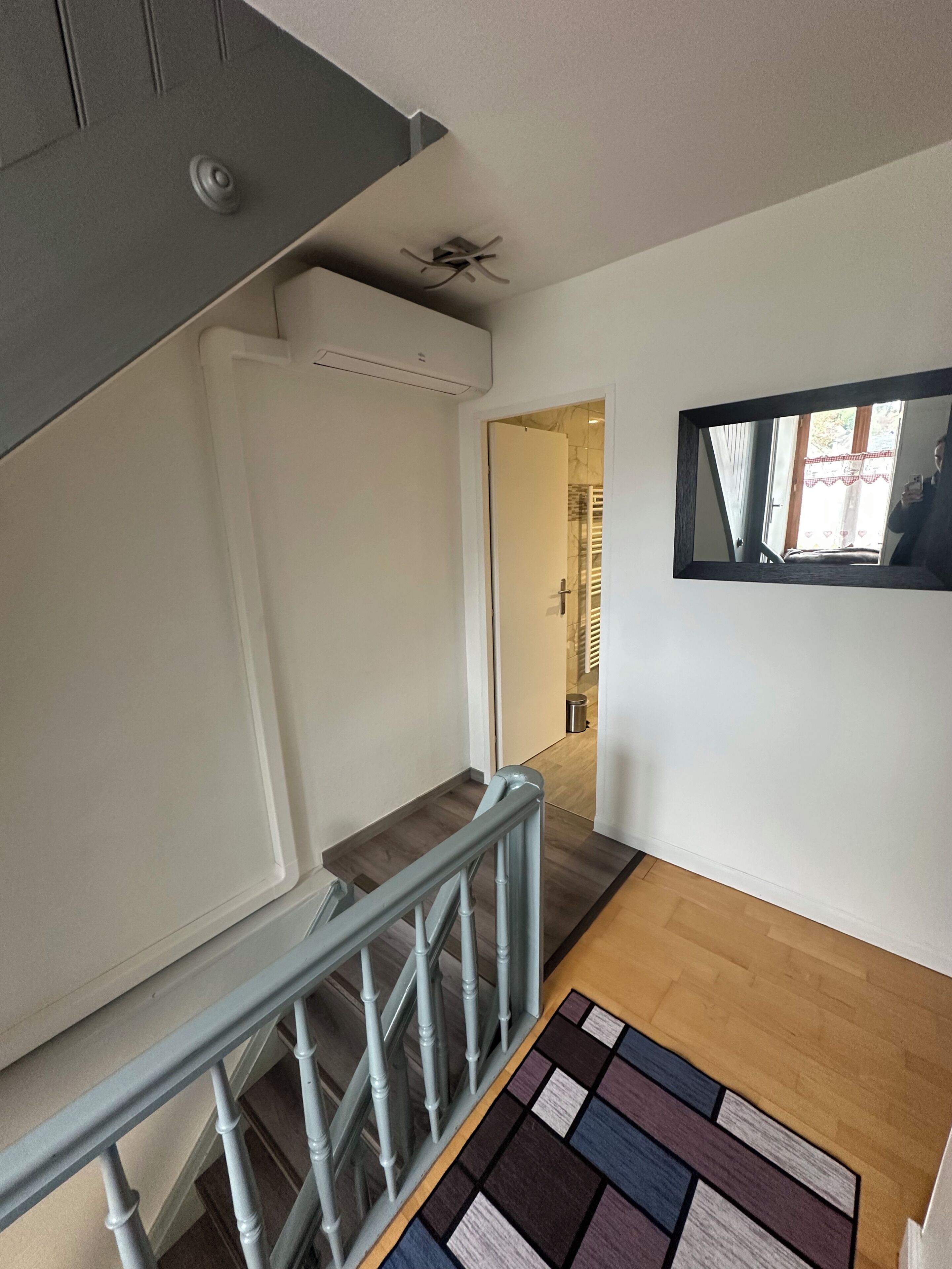 Un escalier avec une rampe en bois et un tapis à motifs au bas.