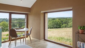 A room with large windows, a dining table, and chairs. - Le pré de Régine et Joseph (Malmedy)
