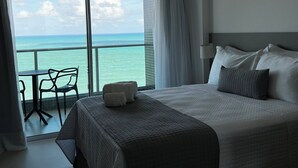 Ein Hotelzimmer mit einem großen Bett, einem kleinen Tisch mit Stühlen und Meerblick.