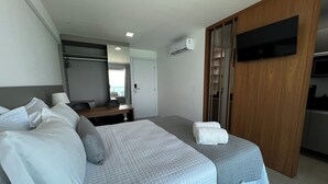 Ein Hotelzimmer mit einem Bett, einem Schreibtisch, einem Sessel, einem Fernseher und einem Kleiderschrank.