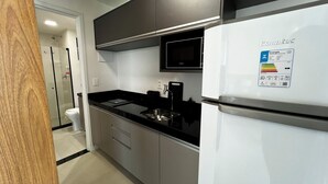 Eine moderne Küche mit Kühlschrank, Mikrowelle und einer Duschkabine aus Glas.