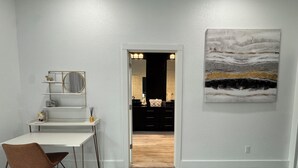 A room with a desk, chair, and a painting on the wall.