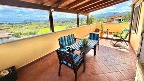 A covered patio with a wooden ceiling, a table with chairs, and a view of a green landscape. - Belvedere Penthouse - Metro C - Parking Space. Panoramic view of the Hills of Rome. (Roma)