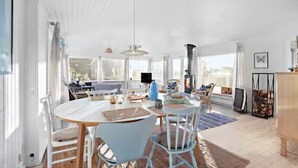 Un comedor amplio y luminoso con una mesa redonda y sillas, ventanas grandes y vistas al exterior.