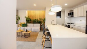 Eine moderne Küche mit Kochinsel, Barhocker und einem Essbereich mit Sofa und Couchtisch.