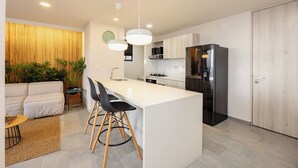 Eine moderne Küche mit einer zentralen Kochinsel, schwarzen Geräten und einem Essbereich mit einer Couch und Stühlen.