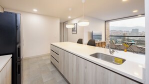 Eine moderne Küche mit einer großen Kochinsel, einem eingebauten Backofen und Blick auf die Stadt durch große Fenster.