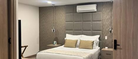 A modern bedroom with a large bed, bedside tables, an air conditioning unit, and a door with the number 406.