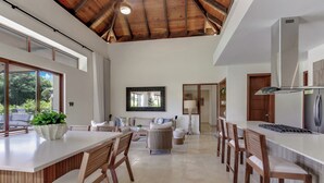 A spacious kitchen with a large island, wooden chairs, and a high ceiling with exposed beams. - Stylish Newly Built Villa in Cap Cana  (Punta Cana)