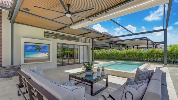 A modern outdoor living area with a pool, seating, and a ceiling fan. - Stylish Newly Built Villa in Cap Cana  (Punta Cana)