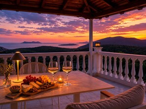 Una terraza con una mesa dispuesta para una comida, con vistas a un hermoso atardecer.