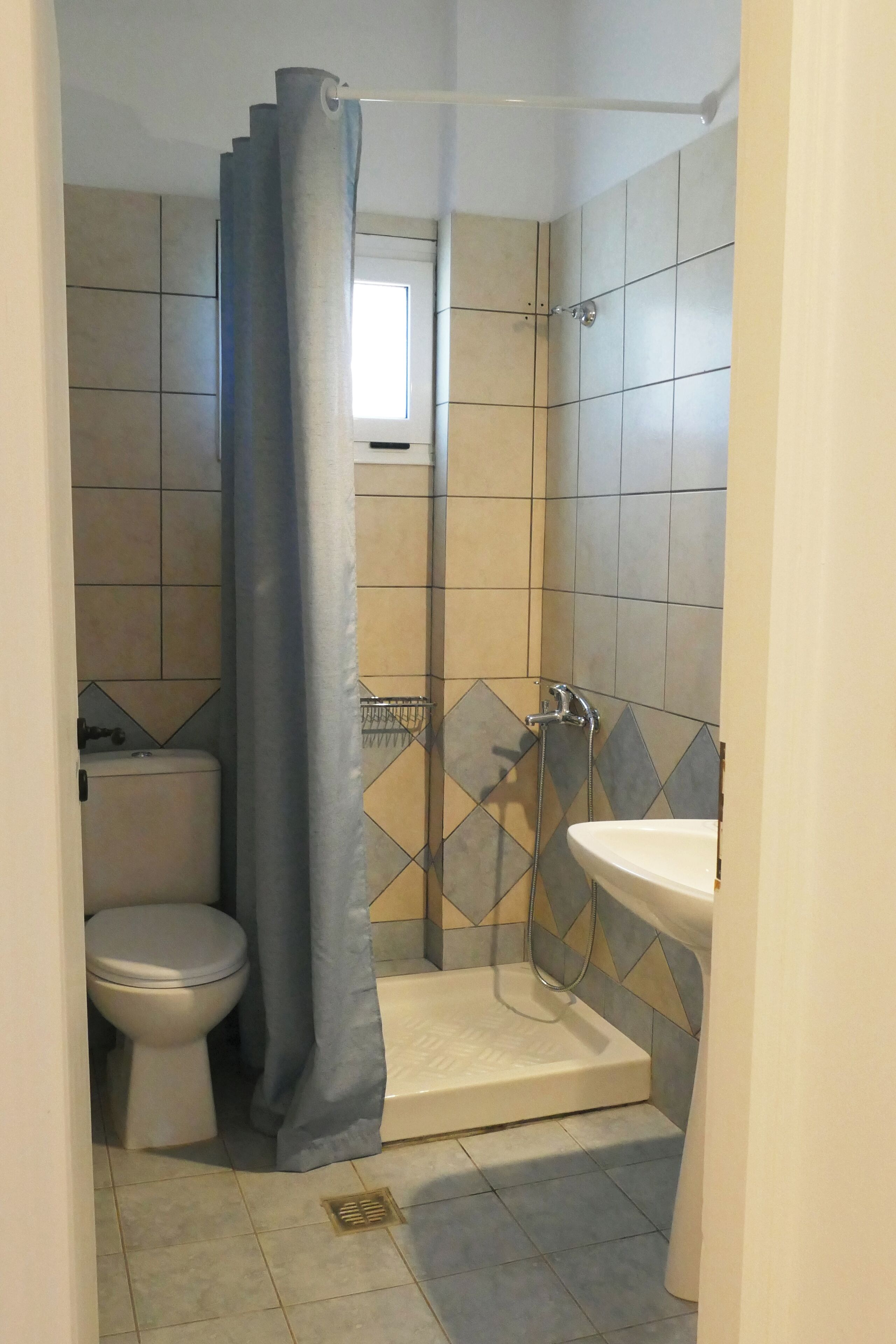 A bathroom with a shower, toilet, and sink.