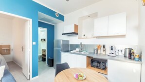 Una cocina moderna con armarios blancos, un refrigerador de acero inoxidable y un microondas. Hay una mesa de comedor con un plato de comida.