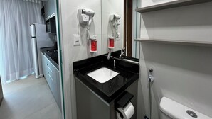 Ein modernes Badezimmer mit einem schwarzen Waschbecken, einer Toilette und einem an der Wand befestigten Fön.