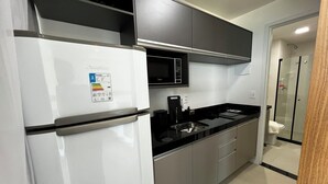 Eine moderne Küche mit einem weißen Kühlschrank, einer Mikrowelle und einer schwarzen Arbeitsplatte.