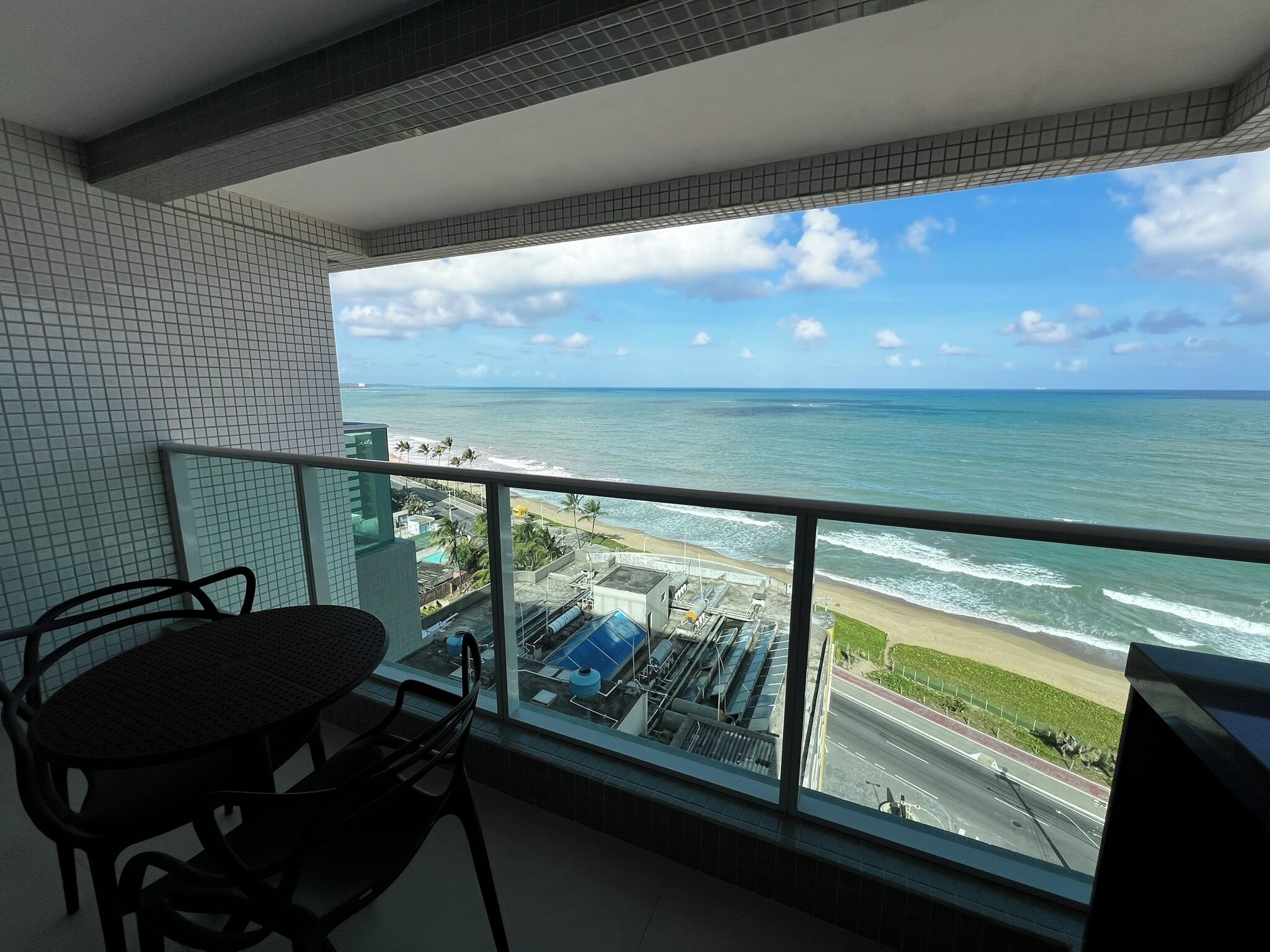 Ein Balkon mit Blick auf das Meer und eine Straße.