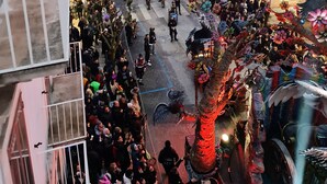 A crowded street scene with buildings and a tree decorated with flowers.