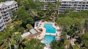 Ein Resort mit mehreren Schwimmbecken, umgeben von üppiger Vegetation und einem großzügigen Gebäudekomplex.