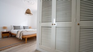 A bedroom with a bed, bedside tables, a hanging light fixture, and a wardrobe with louvered doors. - Amaro Oasis by LovelyStay (Funchal)