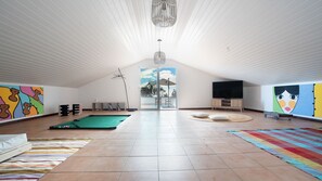 A spacious room with a pool table, a large window, and a TV.
